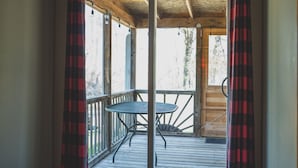 A wooden deck with a metal table and chairs, a wooden ceiling, and a view of trees outside. - Cozy 1BR Lakefront Cabin w/ Private Launch & Dock (Backus)