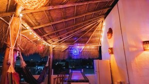 A rooftop terrace with a thatched roof, string lights, and a view of the city at night. - STUNNING SKY DECK/FERRY & BEACH 2min/POOL/SLEEPS 5-16/24-7 SECURITY/GARDEN PATIO (Cancun)