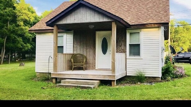 A small, single-story house with a porch, a front door, and a small window on the side. - Newly remodeled, cozy cottage only steps away from the Katy Trail in Windsor, MO (Windsor)
