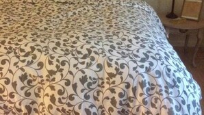 A bed with a patterned bedspread and a wooden headboard. - Newly remodeled, cozy cottage only steps away from the Katy Trail in Windsor, MO (Windsor)