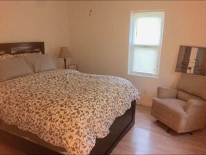 Cozy retreat with a large bed, bedside table, and comfortable chair.