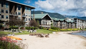A resort with multiple-story buildings, a sandy beach, and a mountainous backdrop.