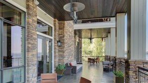 A covered patio area with stone walls, a round wooden table, and outdoor seating.