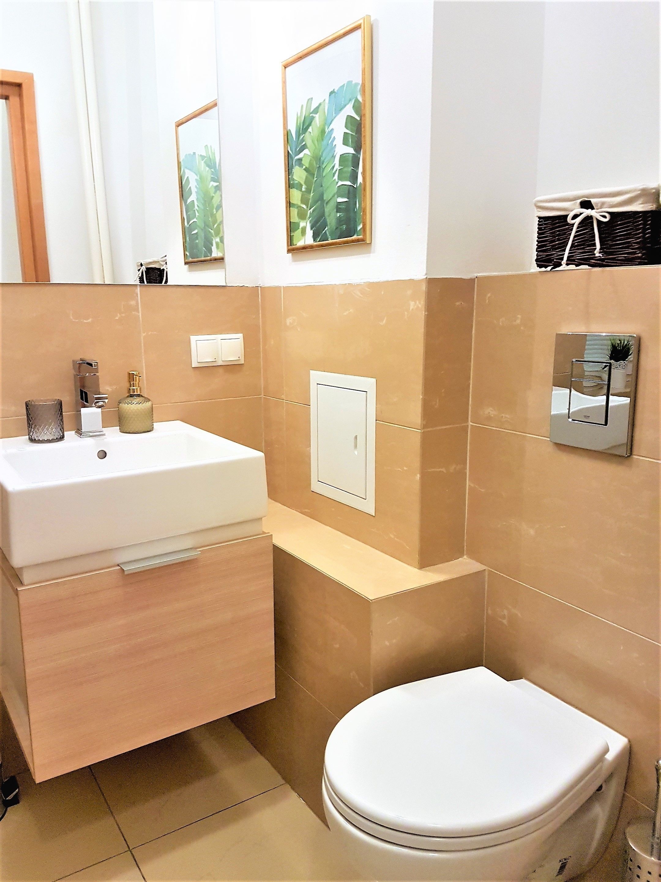 A bathroom with a white sink, a toilet, and a mirror. There are two framed pictures on the wall.