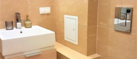 A bathroom with a white sink, a toilet, and a mirror. There are two framed pictures on the wall.