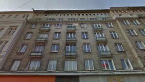 Un edificio de varios pisos con una fila de ventanas en cada planta, balcones y un letrero que dice 