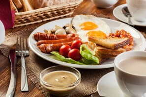 Une assiette de nourriture pour le petit-déjeuner comprenant des saucisses, des œufs, des toasts, des haricots et des tomates.