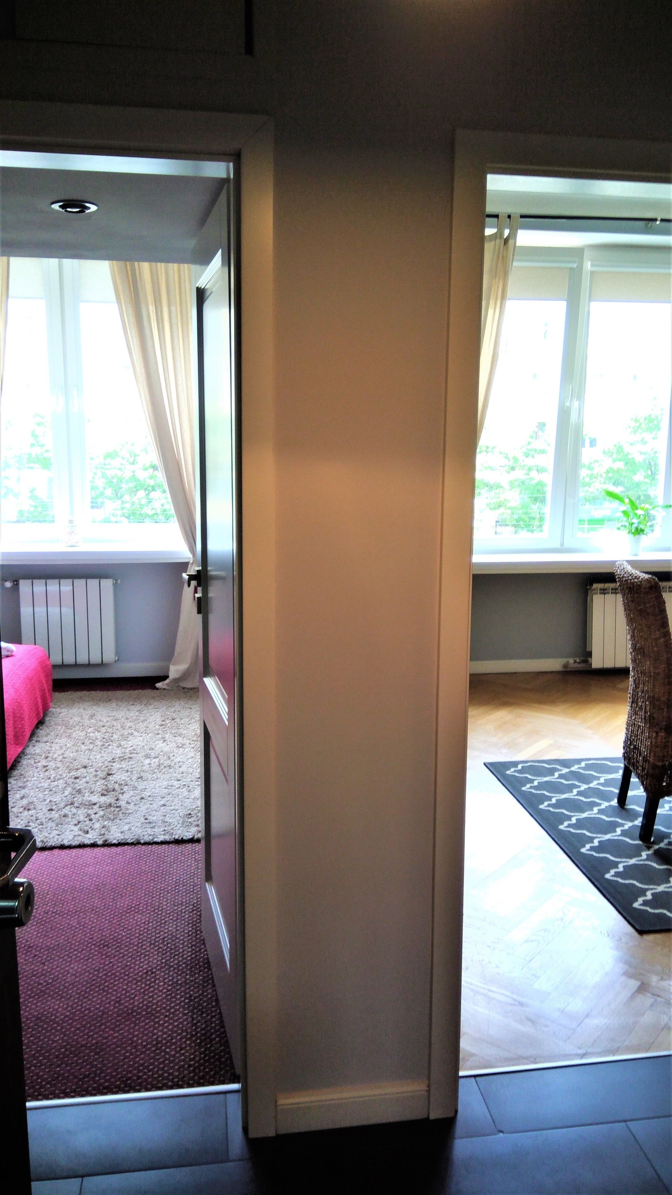 An open door leading to a room with a bed, a radiator, and a window with curtains.