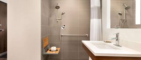 A modern bathroom with a shower, a sink, and a mirror.