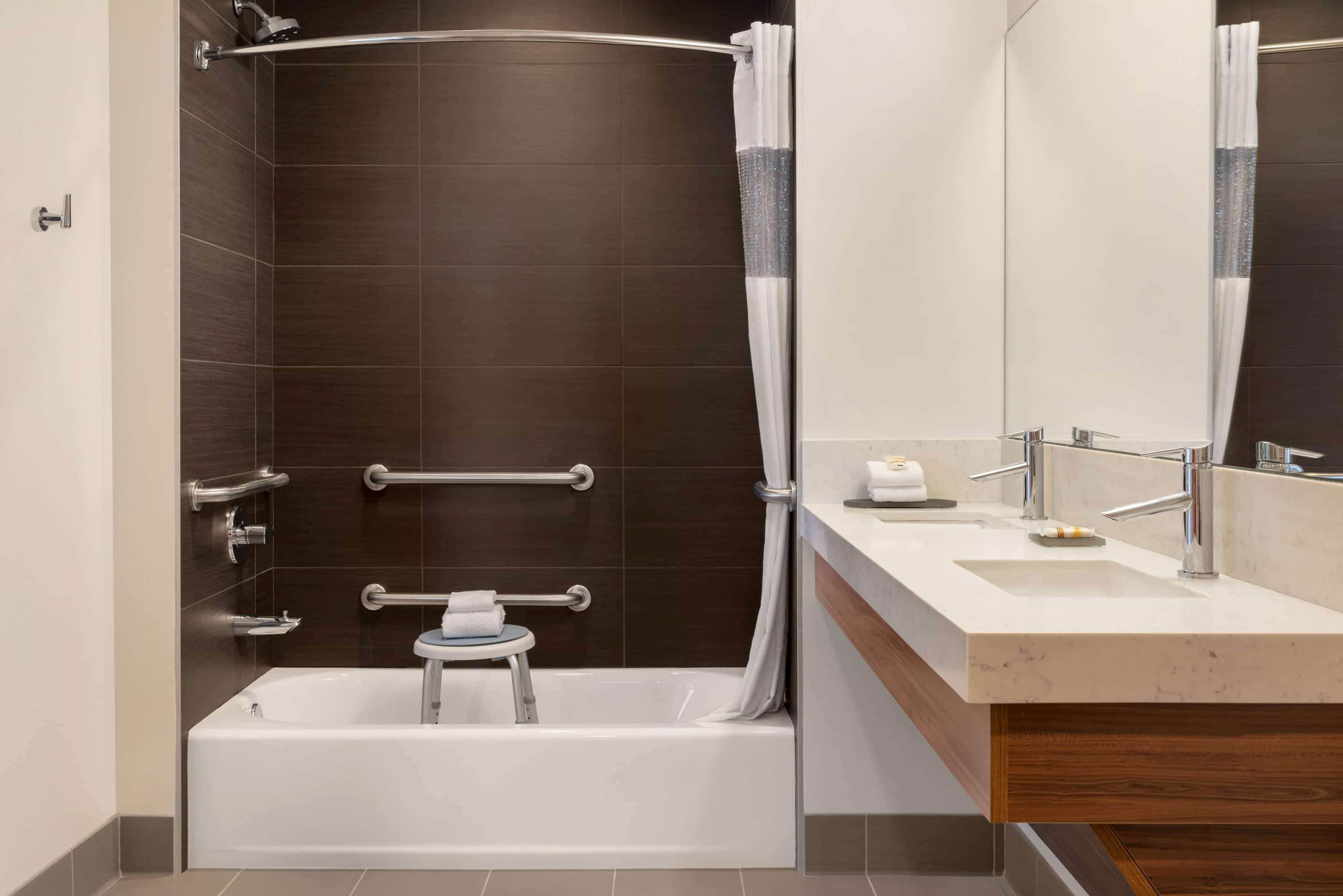 Een moderne badkamer met een bad, een wastafel met spiegel en een douchecel met een gebogen glazen deur.