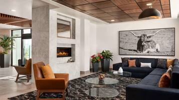A modern living room with a fireplace, leather sofas, a large black and white artwork, and a ceiling with wooden panels.