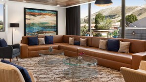 A modern living room with a sectional sofa, glass coffee tables, and a large abstract painting.