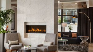 A modern lobby with a fireplace, two armchairs, a round coffee table, a sofa, and a floor lamp.