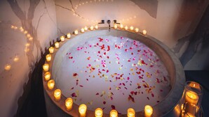 Una bañera rodeada de velas y pétalos de flores.