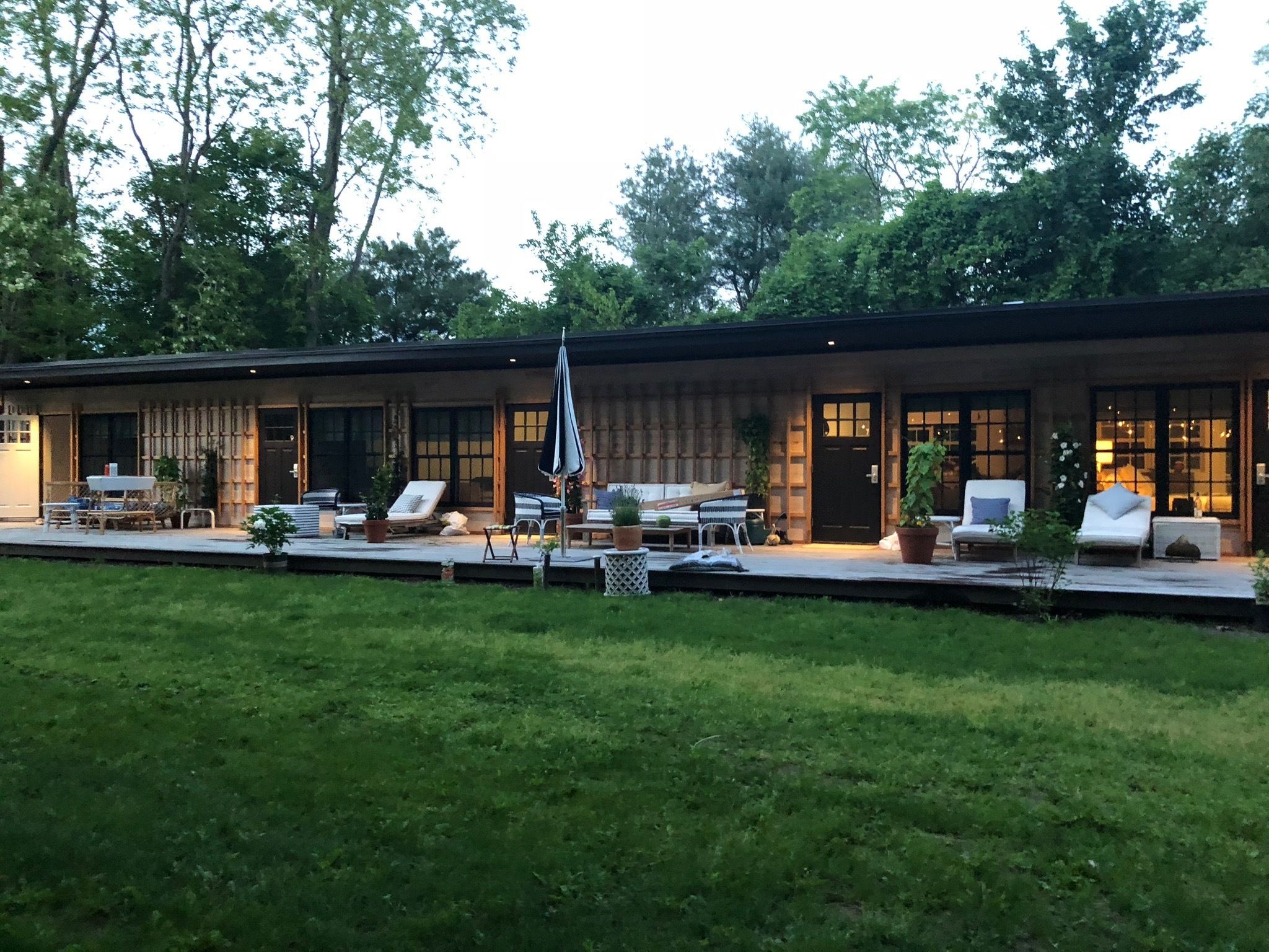 A modern building with a covered outdoor seating area, including lounge chairs and a table.