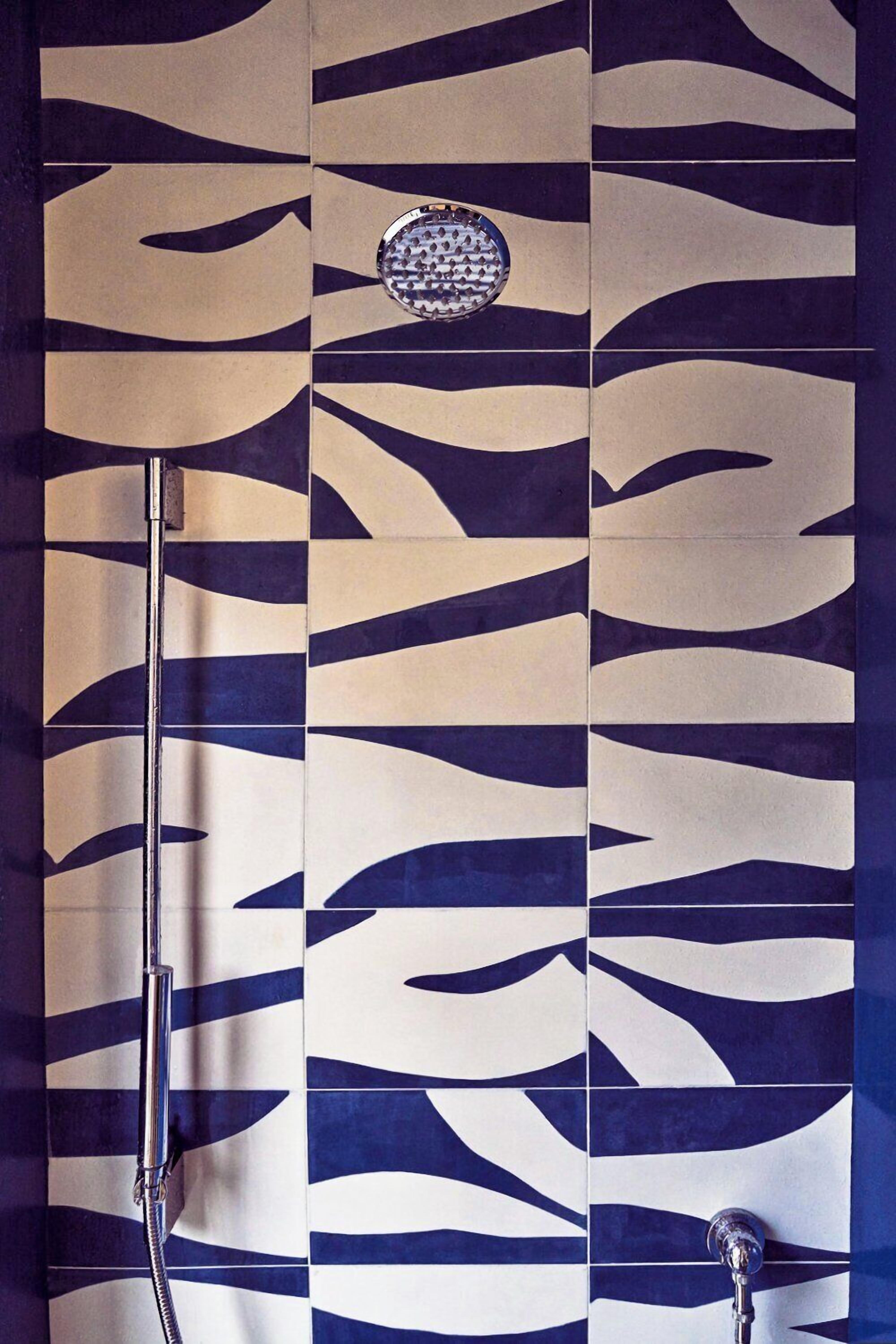 Un baño con diseño de azulejos estampados y un cabezal de ducha.