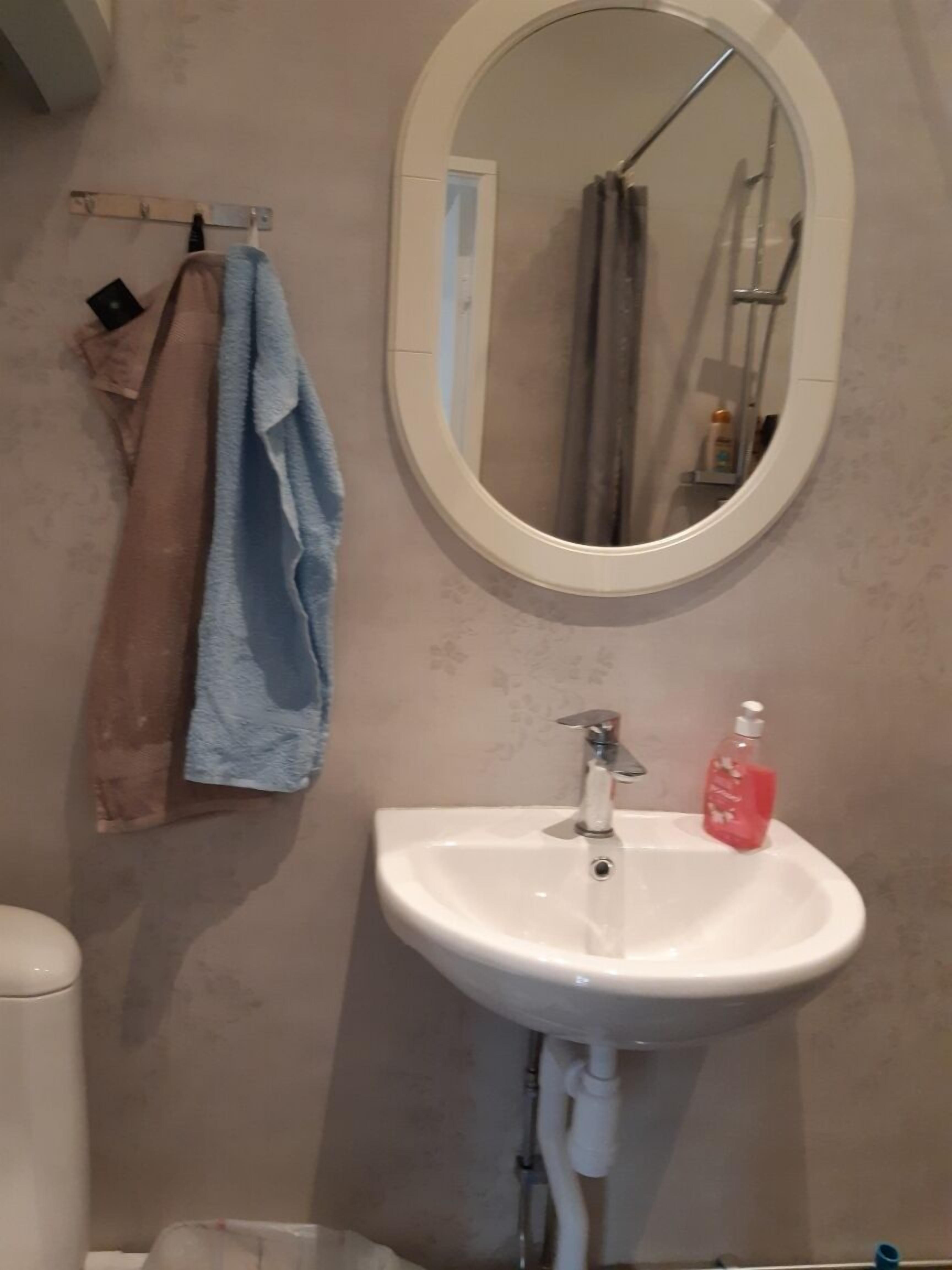 A bathroom with a white sink, a mirror, and a towel rack with a blue towel.