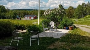A flagpole with a flag, outdoor seating, and a rural landscape. - Täljegården Lantgårdshotell (Erikslund)