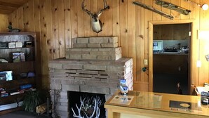 Een rustiek interieur met een stenen open haard, houten wanden en een opgezette hertenkop.