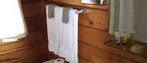 A wooden-paneled bathroom with a toilet, sink, and a towel hanging on a rack.