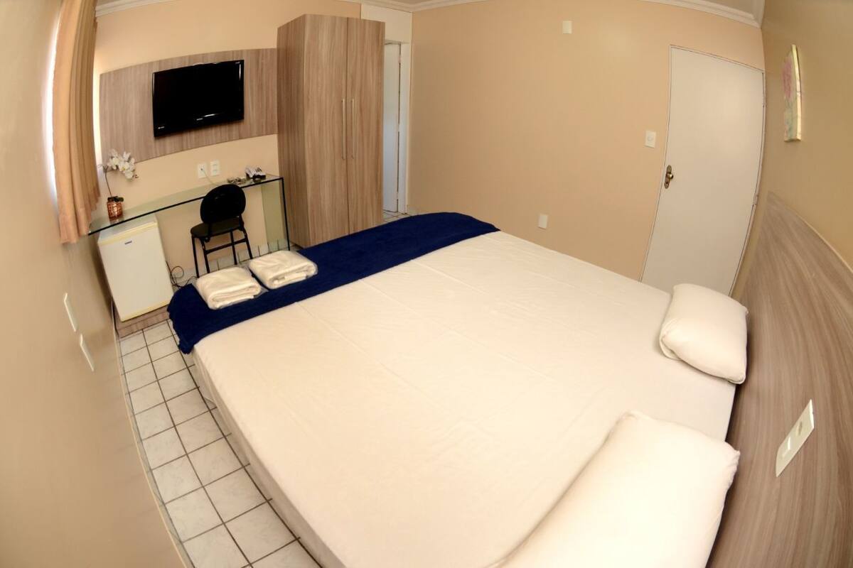 A hotel room with a bed, a desk, a television, and a wardrobe.