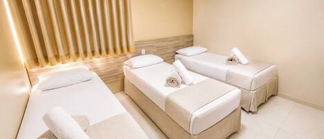 A hotel room with two beds, a headboard, an air conditioning unit, and a curtain.