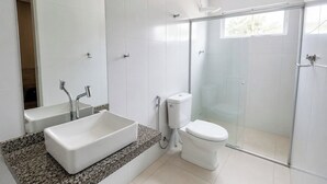 Un baño moderno con un lavamanos grande y rectangular, un inodoro y una ducha con cerramiento de vidrio.
