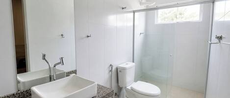 A modern bathroom with a large rectangular sink, a toilet, and a glass-enclosed shower.