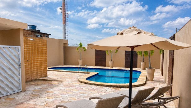 Un área de piscina con dos jacuzzis, sillas de descanso y una sombrilla.