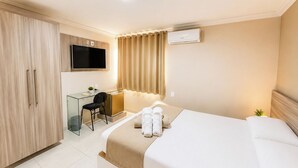 Una habitación de hotel con una cama, un escritorio, una silla, un televisor y un equipo de aire acondicionado.