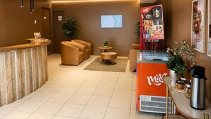 Un hall de hotel con mostrador de recepción, zona de estar y una máquina de café.