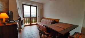 A room with a bed, a desk with a lamp, a television, and a window with a view. - Residence Weissthor (Macugnaga)