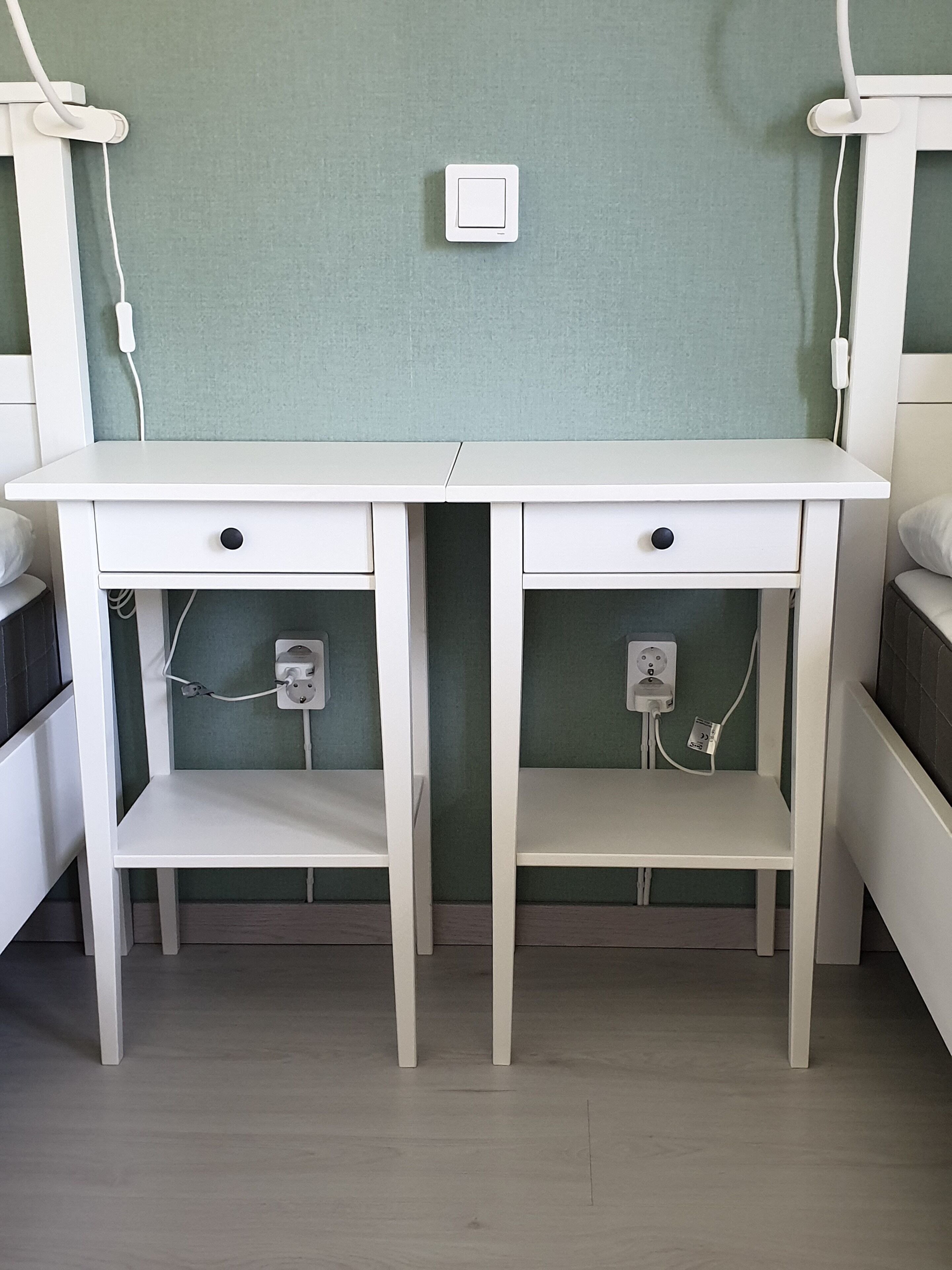 Een wit bureau met twee lades en twee planken, geplaatst tussen twee bedden.