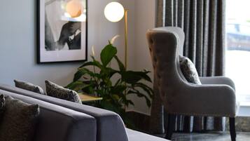 En moderne stue med en grå sofa, en polstret lænestol og to billeder i rammer på væggen.