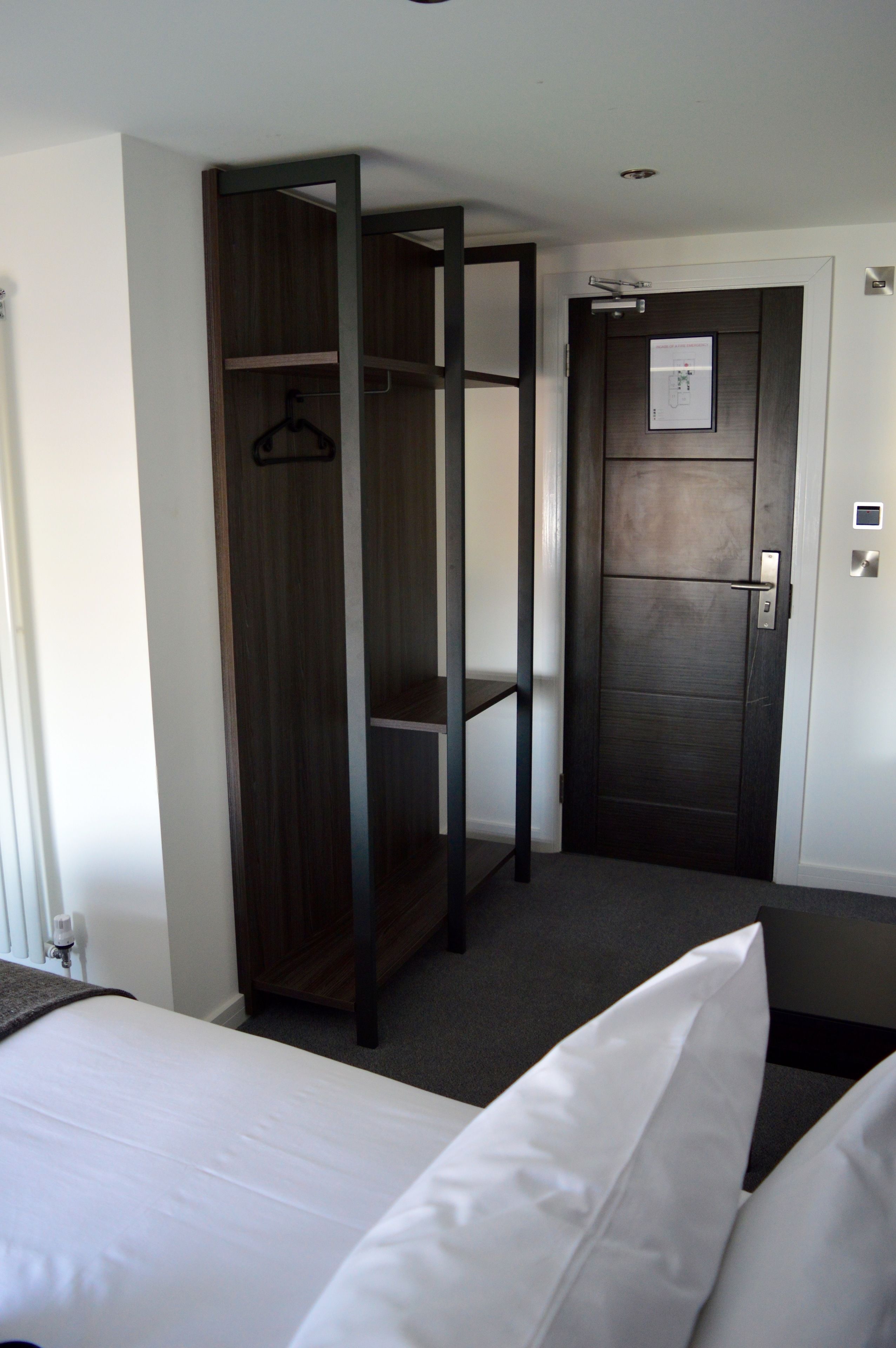 Een hotelkamer met een bed, een kledingkast en een deur met een beveiligingspaneel.