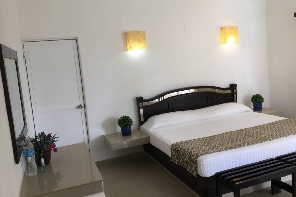 Een slaapkamer met een bed, nachtkastjes, wandlampen, een deur en een bankje.