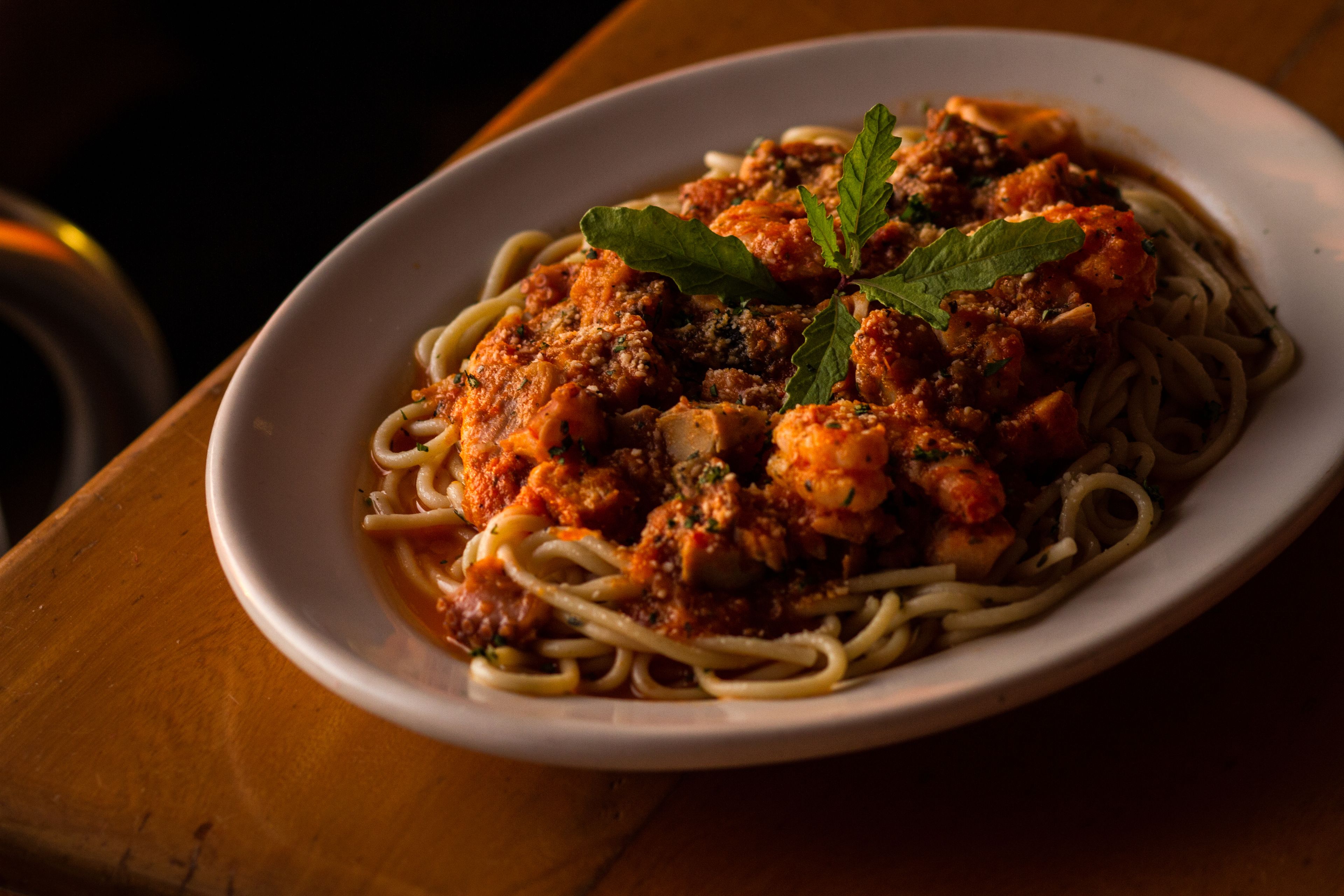 A plate of spaghetti with meatballs and tomato sauce, garnished with a leaf.