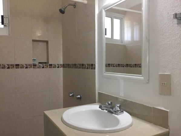 A bathroom with a white sink, a mirror, and a shower.