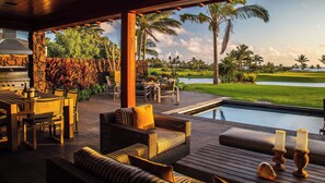 A covered outdoor area with a pool, dining setup, and lounge seating.