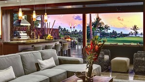 A modern lounge area with a sofa, chairs, a bar, and a view of a golf course.