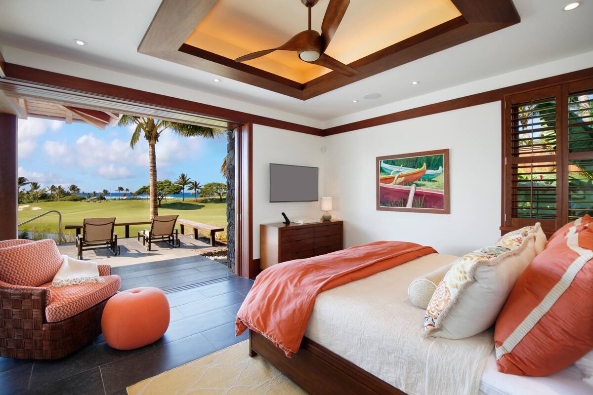 Ein Schlafzimmer mit einem großen Bett, einem Fernseher und Blick auf einen Golfplatz.