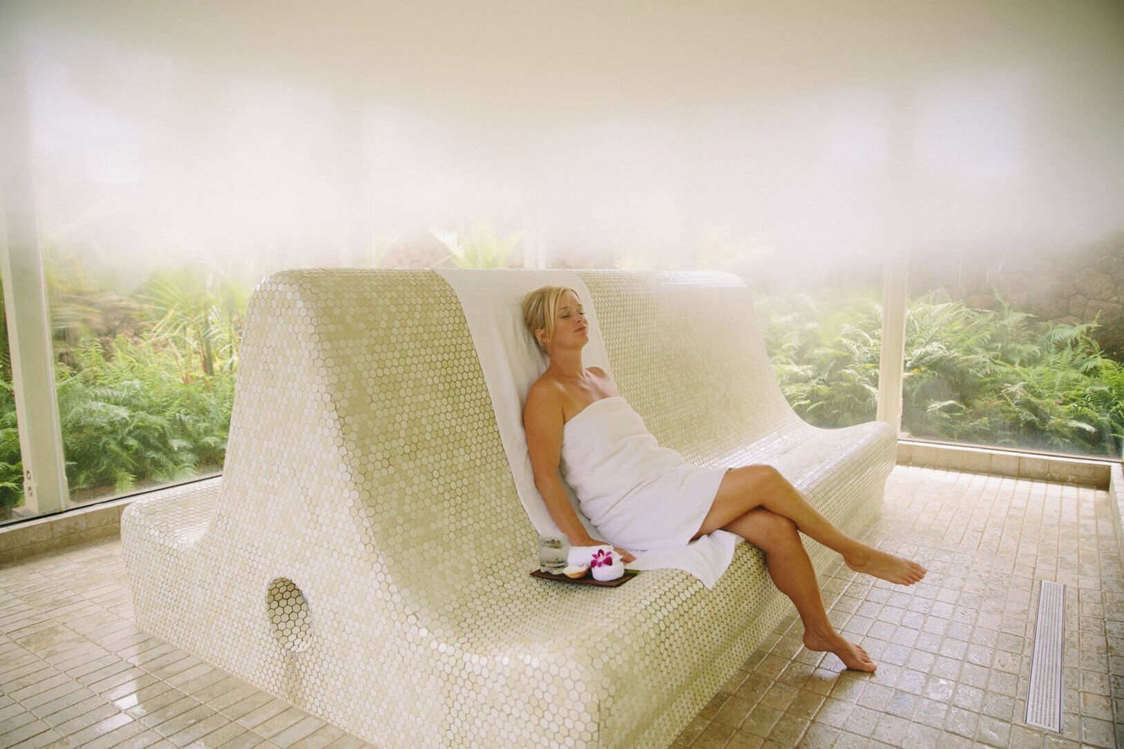 A person relaxing in a hexagonal-patterned lounge chair with a view of greenery outside.