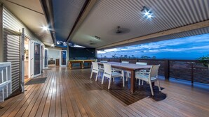 Una terraza de madera con mesa de billar, sillas y una mesa de comedor.