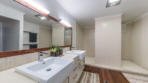 Un baño moderno con dos lavamanos, un espejo grande y una zona de ducha.