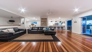 Una sala de estar moderna con un sofá seccional de cuero negro, piso de madera y un comedor con barra.