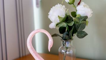 A pink swan figurine next to a vase with white flowers on a wooden surface.