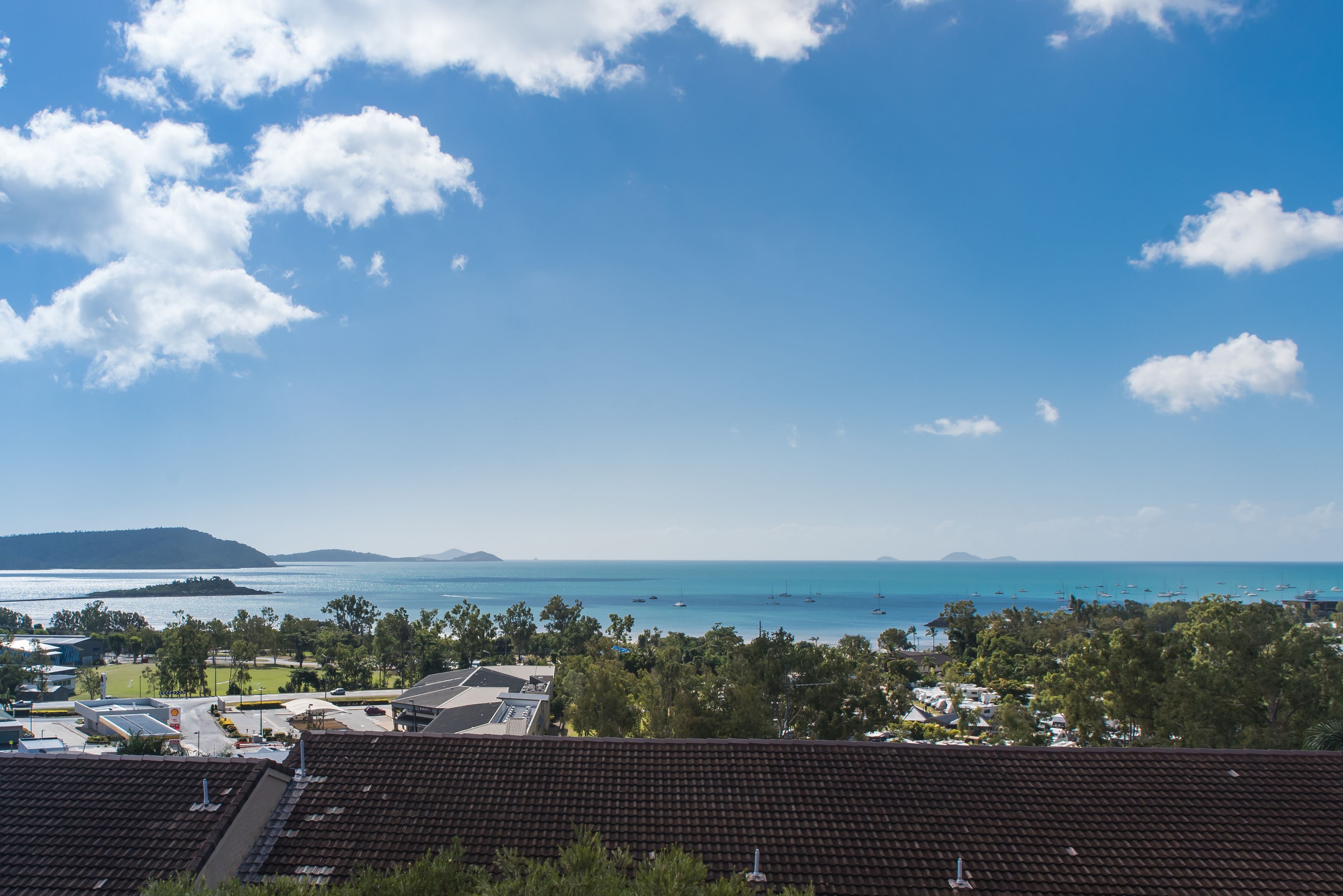 A coastal view with a clear sky, a beach, and a marina.