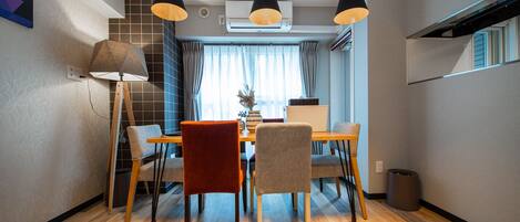 Un comedor moderno con una mesa de madera, cuatro sillas y lámparas colgantes.