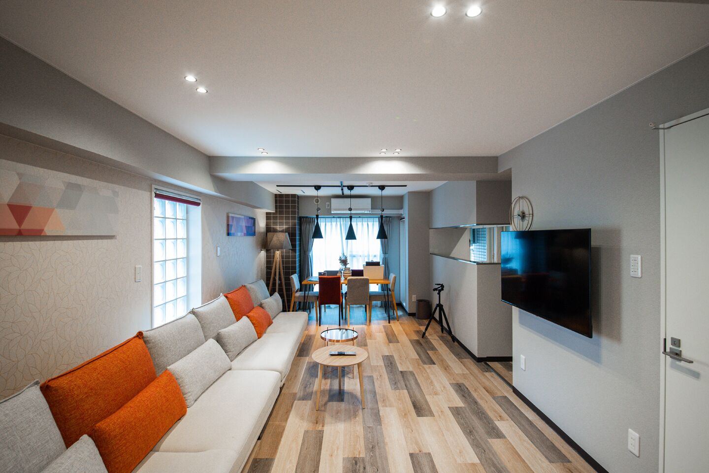 Una sala de estar moderna con un sofá, un televisor de pantalla plana y un comedor al fondo.