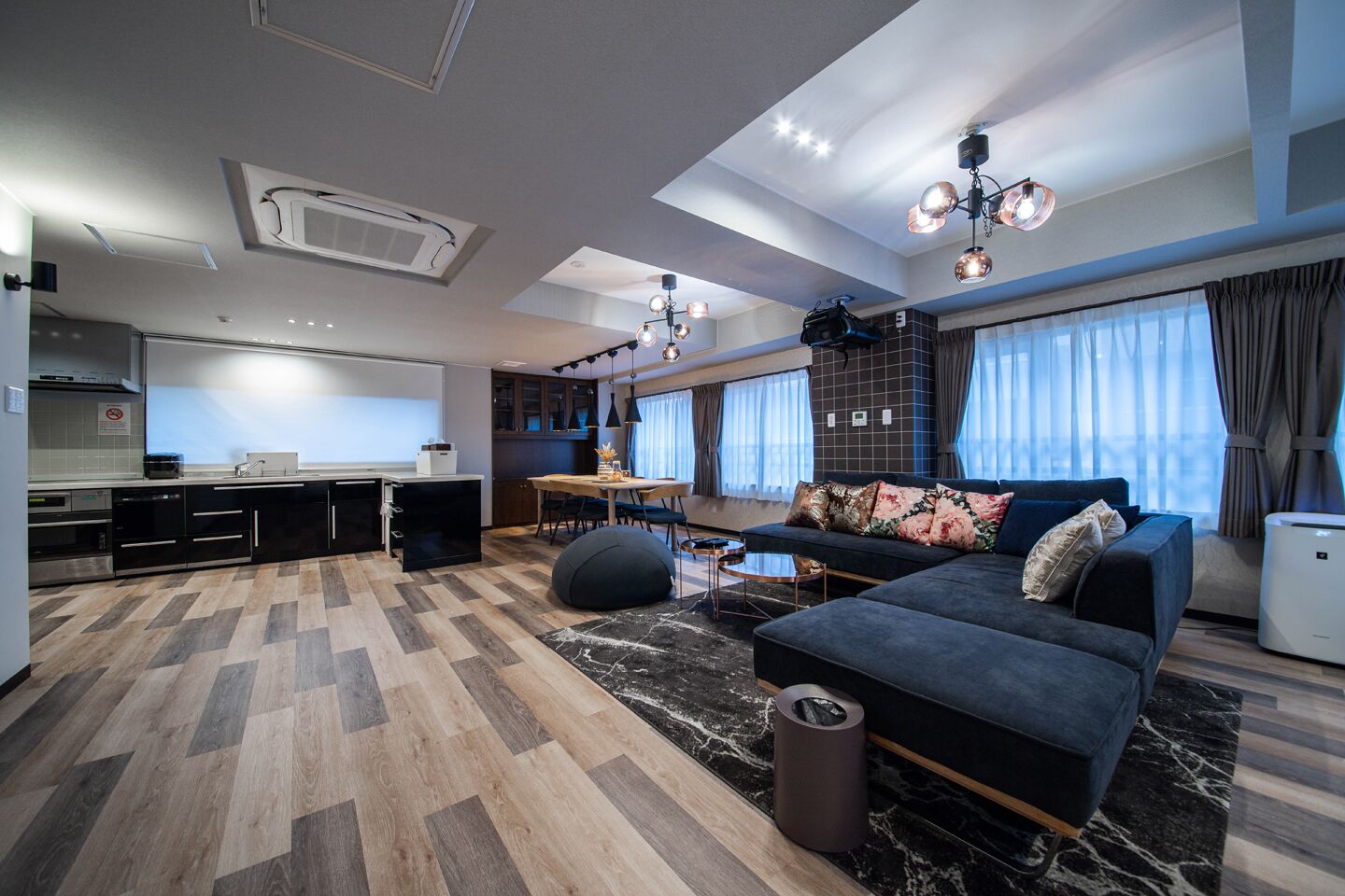 A modern living space with a kitchen, dining area, and a sofa set.